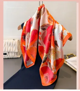 Détail d'un foulard en soie à imprimé floral vibrant avec des tons orange et rouges