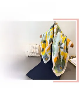 Détail d'un foulard en soie aux motifs floraux jaunes et verts drapé sur un cintre