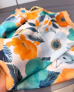 Gros plan d'un foulard en soie aux imprimés floraux orange et bleu et texture satinée