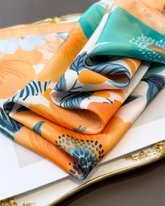 Gros plan d'un foulard en soie avec imprimé floral orange vif et finition satinée