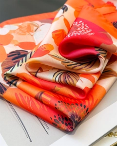 Détail d'un foulard en satin de soie avec motifs floraux abstraits orange et coutures nettes
