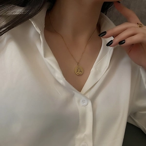 Collier médaille dorée avec gravure de portrait abstrait porté par un mannequin élégant
