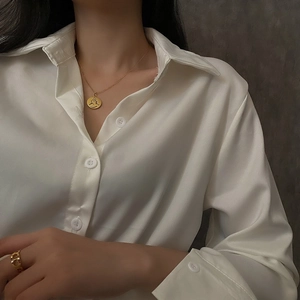 Collier médaille dorée avec pendentif chat et bague ajourée sur une chemise en satin