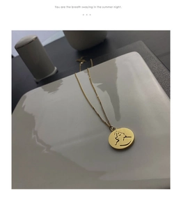 Détail du collier médaille doré avec portrait abstrait posé sur une plaque céramique