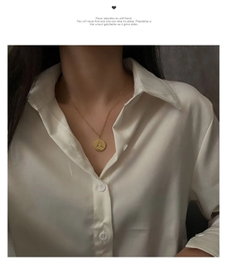 Détail d'un collier doré minimaliste avec pendentif visage abstrait sur femme