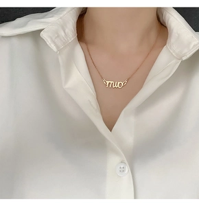 Close-up of golden letter pendant with wings on a minimalist stainless steel chain