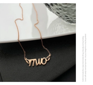 Detail view of rose gold necklace with muo letter pendant and wing charm on O-chain