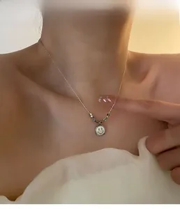 Close-up of model wearing a titanium steel smiley face necklace with shell inlay