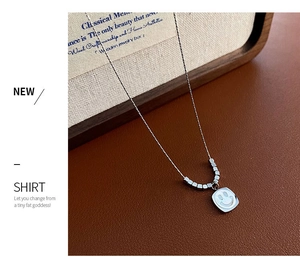 Detailed 45-degree angle of silver smiley face necklace on premium brown leather surface