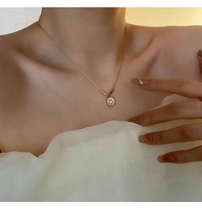 Close-up of golden shell smiley face pendant necklace on model with bead details