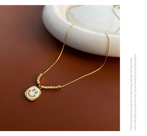 Close-up of golden necklace with a white shell smiley face pendant on leather texture