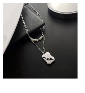 Close-up of double layer titanium necklace with natural pearls and engraved tag