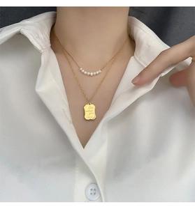 Macro view of double-layer necklace with pearls and 'Do what you love' gold pendant