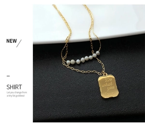 Detail of double-layer gold necklace featuring natural pearls and engraved tag pendant