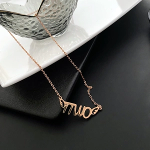 Minimalist rose gold necklace with 'TWO' letter pendant and wing design on white ceramic