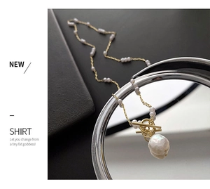 Detail of gold pearl necklace with baroque pendant and OT toggle clasp on mirror
