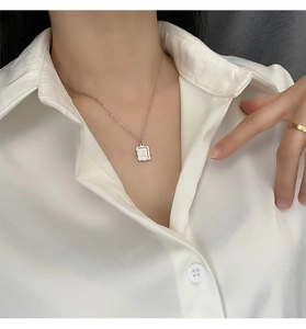 Macro shot of rectangular pendant with engraved text on minimalist gold chain necklace