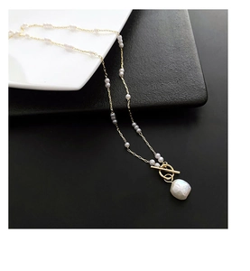 Detail of freshwater baroque pearl pendant with gold OT buckle and grey pearl accents