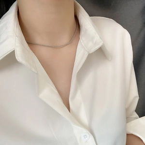 Macro shot of a delicate silver-colored sparkling chain necklace on woman's neck