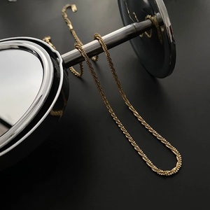 Close-up of golden sparkling twisted chain necklace against a dark background
