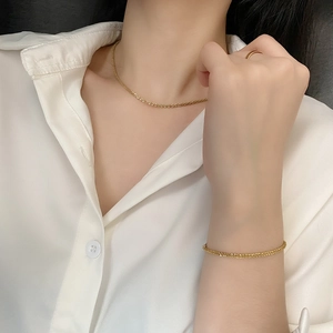 Macro detail of delicate shimmering gold necklace and bracelet set on a model