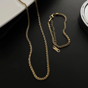 Detailed close-up of gold titanium steel twisted chain necklace and bracelet set