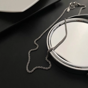 Detail of silver twisted chain necklace with lobster clasp and shiny metallic finish