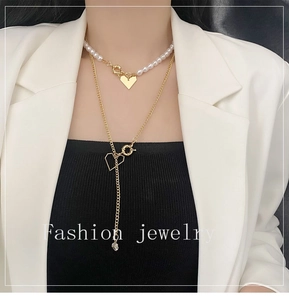 Détail des colliers superposés avec perles et cœurs dorés portés par un mannequin