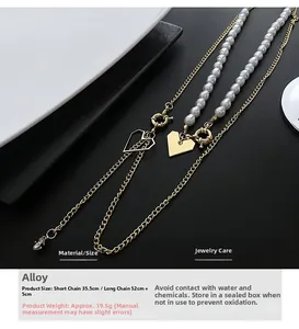 Collier double couche doré avec perles et pendentifs cœur sur un plat noir et blanc