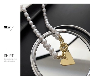 Gros plan d'un collier de perles superposé avec pendentif cœur doré et fermoir à maillons