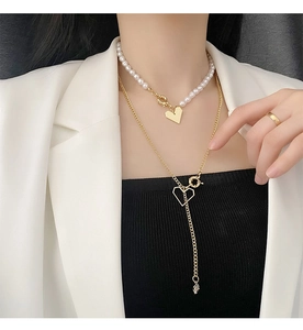 Détail d'un ensemble de colliers dorés avec perles et pendentifs cœur sur un mannequin