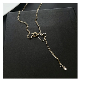 Détail d'un collier doré avec pendentif cœur ajouré et pierre en zircon étincelante