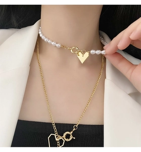 Vue détaillée du collier de perles multicouche avec pendentifs cœur dorés sur mannequin
