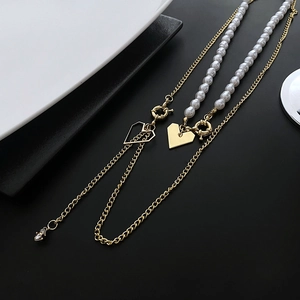 Collier multicouche doré avec perles et pendentifs cœur sur fond bicolore moderne