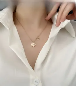 Mannequin portant un collier pendentif lettre M en titane rose gold avec une chemise blanche