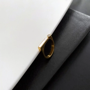 Detailed close-up of golden shell and zircon inlay on a modern minimalist ring