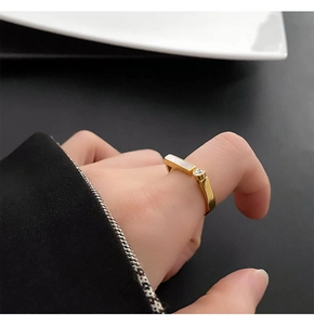 Close-up of gold steel ring with white shell and zircon on a model's hand