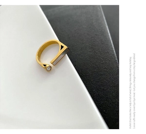 Macro detail of geometric gold ring featuring white shell inlay and round cubic zirconia