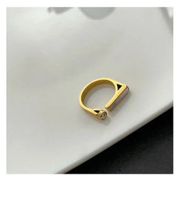 Detailed view of an open gold ring with a geometric shell inlay and round zirconia stone