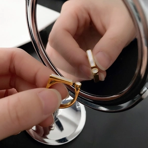 Minimalist gold titanium ring with natural shell and zircon shown on a mirror surface