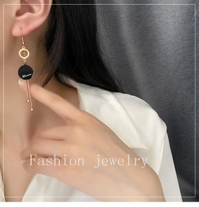 Detail of long fringe tassel earrings featuring Love engraved black disc and gold beads