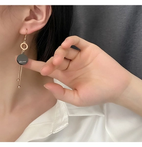 Detail of gold tassel earrings with Love pendant and fine chains on model