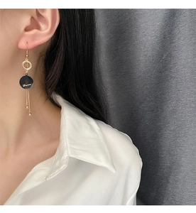 Close-up of long gold tassel earrings with Love engraving on a minimalist model