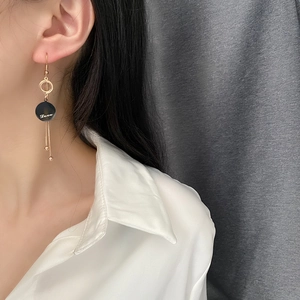 Elegant gold titanium steel tassel earrings with black 'Love' charm on a female model