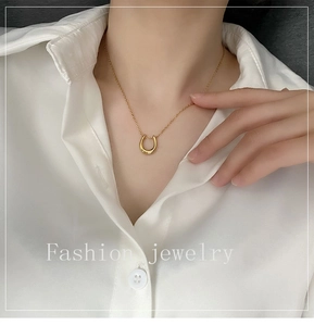 Polished gold U-shaped pendant necklace on model wearing white shirt for chic look