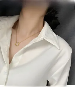 Elegant gold U-shape horseshoe pendant necklace shown on a model in a silk blouse