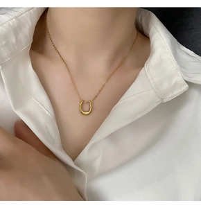 Close-up of polished gold horseshoe U-shaped pendant on a minimalist chain for women