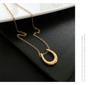 Detailed view of polished golden U-shaped pendant necklace with elegant O-link chain