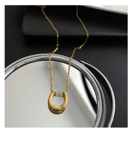 Detailed view of mirror-polished gold U-shaped pendant on a minimalist necklace
