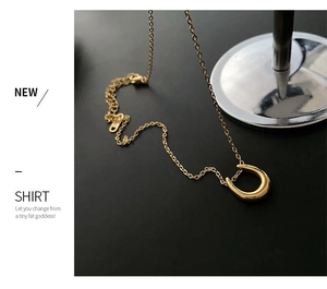 Close-up of golden stainless steel U-shaped necklace pendant on black background